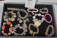 Top view showing all twelve mixed charm and stretchy bracelets laid on black background.