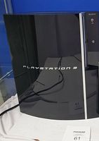Front view of black Sony PlayStation 3 console with shiny curved design and branding visible