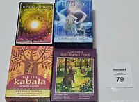 Four tarot and oracle card sets with guidebooks displayed flat: Divine Guidance, Energy Oracle, Ask the Kabala, and Children's Spirit Animal Cards.