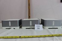 Front view of three Sonos CONNECT:AMP units on white surface
