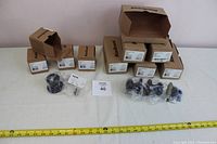 View of boxed and unpackaged door knobs and their hardware laid out on a surface with a measuring tape for scale.