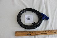 Full view of the coiled black cable bike lock with ruler for size reference, showing the length approximately 36 inches when coiled.