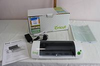Cricut Mini cutting machine with power adapter, USB cable, quick start guide, cutting mat, and original box.