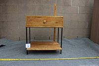 Front view of mango wood side table showing drawer, bottom shelf and metal legs.