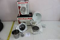 Photo showing KitchenAid citrus juicer attachment pieces with original boxes in background.