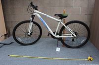Full side view of the white Mongoose mountain bike showing frame, wheels, seat and handlebars.