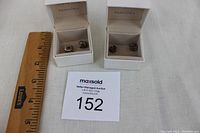 Four Pandora charms in two white Pandora Disney Parks boxes with MaxSold auction tag and ruler for scale