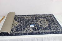 Rolled blue and beige runner rug showing backside and pattern on the surface.