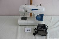 Full view of Singer Featherweight II sewing machine with attached pedal cord coiled in front.