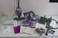 Full lot display showing steam mop with attached pad, handheld steamer, cleaning pads, floor glider, and manuals on white table