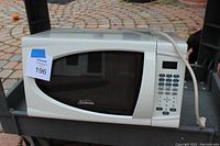 Sunbeam white microwave oven with keypad and digital display, power cord visible.
