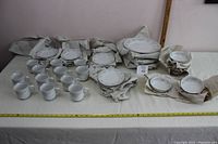 Full view of the dishware set arranged on a table, showing cups, plates, and bowls wrapped in paper