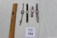 Photo showing all four watches next to a ruler for size reference
