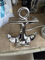 Front view of shiny hollow decorative anchor with smooth reflective silver finish on countertop.