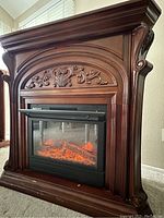Dark wood fireplace mantel with electric insert showing flame effect