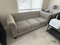 Front view of grey 3-seater sofa showing tufted backrest and rolled arms.