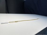 Full length of the gold-plated chain necklace laid out on white surface showing the entire 20 inch length.