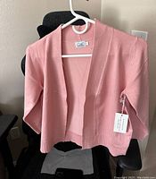 Front view of dusty pink open-top shirt with original tags on a hanger.