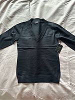 Full view of the black women's sweater laid flat on a surface showing front and sleeves.