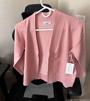 Front view of dusty pink women's open-top shirt hanging on hanger showing original tags and ribbed hem.