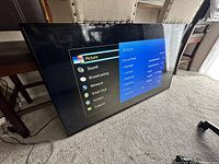 Front-angled view of TV powered on showing Picture settings menu on carpeted floor