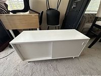 Front view of white TV stand shelf showing sliding doors and minor stain on surface