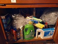 Photo of cleaning supplies under sink including Bar Keepers Friend, Cascade detergent, Dawn dish soap, wipes, cleaning cloths, and pan drying rack.