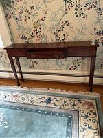 Front view of the mahogany console table against wallpaper