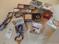 Overview of assorted costume jewelry including necklaces, brooches, and jewelry boxes arranged on a beige surface.