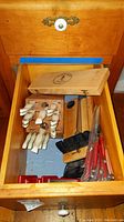 Drawer containing white-handled utensils, wooden block, black Cuisinart sharpener and additional items