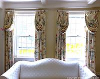Six-piece set of matching floral draperies and valances hung on curtain rods over three window sections with white couch in front, showing length and pattern.