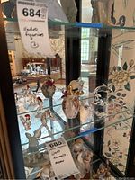 Overhead view of glass perfume atomizer bottle and multiple small glass figurines in a display cabinet