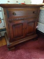 Front view of one Ethan Allen wood night stand showing drawer with round knobs and two-paneled doors below, dark stain finish, visible scratches and wear.