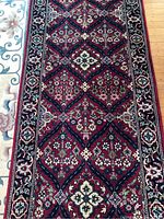 Full view of runner showing repeating diamond medallion pattern on red field and floral motifs