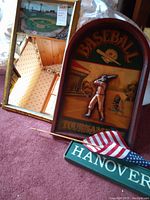 Framed mirror with baseball field image, 3D baseball player wall plaque, Hanover wooden sign and American flag on carpet