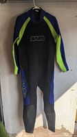 Front view of BARE wetsuit showing black torso, blue sleeves and side panels with lime green stripes, and BARE logo on chest and left leg.