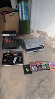 Overview of players, cords, remote, and movies on concrete floor
