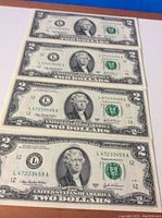 Front view of four 2 dollar bills laid out flat, showing sequential serial numbers L47233458A through L47233461A.