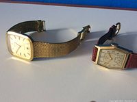 Two vintage men's Elgin watches displayed face up showing dial faces and straps.