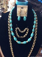 Blue turquoise bead necklace, matching earrings, and bracelet on display stand