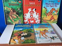 Five hardcover Disney-themed children's books with colorful covers featuring characters Tarzan, 101 Dalmatians, Winnie the Pooh and Tigger Too, Goofy, and Bambi.