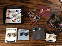 Photo showing assortment of various earrings in different styles and colors arranged on a wooden surface.