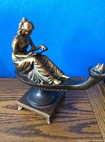 Front side view showing the seated woman on the genie lamp with the flame detail at the spout.