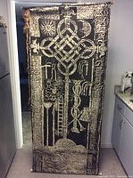 Full length photo of black hanging scroll tapestry with white abstract geometric and symbolic designs.