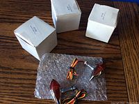 Two boxed sets with three small white boxes, each containing lights, and one set of two loose bullet marker lights wrapped in bubble wrap on a wooden surface.