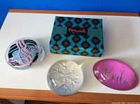 Three glass paperweights with one in original box on white surface against a blue backdrop