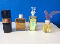 Four perfume bottles against blue background, side view showing Chanel and other bottles