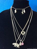 Five sterling silver necklaces displayed on black mannequin bust. Variety of pendant styles visible, including Disney character charms, heart pendant, elephant and gemstone charm.