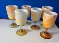 Front view of 6 vintage hand-blown stone glasses showing their unique swirl patterns and coloration.