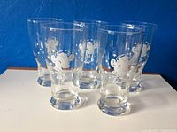 Photo showing all five vintage milk glasses with Elsie the Cow graphic, arranged in a semi-circle.